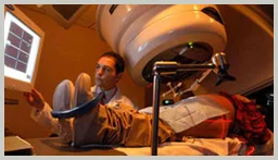 Clinician at the control side of a radiotherapy treatment unit in a darkened treatment room